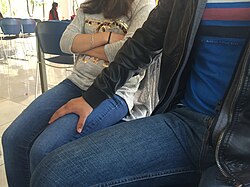 Acted depiction of a man making an unwelcome sexual advance on a woman by putting his hand on her thigh