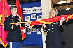 An aide-de-camp holds a brigadier general's flag as a U.S. general[36] unfurls it in March 2020.