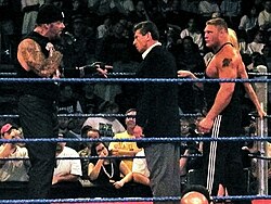 The Undertaker cuts a promo with Vince McMahon, Brock Lesnar, and Sable looking on.