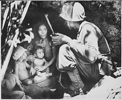 U.S. Marine First Lieutenant Robert B. Sheeks talks a terrified Chamorro woman and her children into abandoning their refuge. Battle of Saipan, 1944.