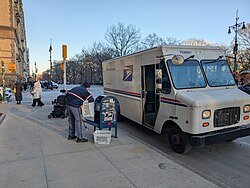 A letter carrier empties a mailbox in New York City