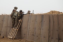 Afghan and U.S. soldiers provide security while standing behind a blast wall made from HESCO bastions Afghanistan, 2012
