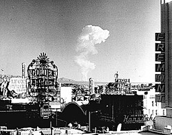 This view of downtown Las Vegas shows a mushroom cloud in the background. Scenes such as this were typical during the 1950s. From 1951 to 1962 the government conducted 100 atmospheric tests at the nearby Nevada Test Site.