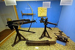 Ancient mechanical artillery: Catapults (standing), the chain drive of Polybolos (bottom center), Gastraphetes (on wall)
