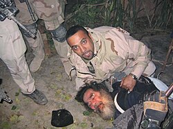 Saddam Hussein being pulled from his hideaway in Operation Red Dawn on 13 December 2003
