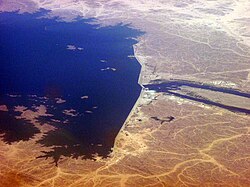 Merowe Dam in Sudan. Hydroelectric power stations that use dams submerge large areas of land due to the requirement of a reservoir. These changes to land color or albedo, alongside certain projects that concurrently submerge rainforests, can in these specific cases result in the global warming impact, or equivalent life-cycle greenhouse gases of hydroelectricity projects, to potentially exceed that of coal power stations.