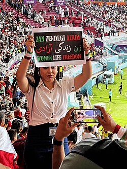 An Iranian fan showing a banner with "Woman, Life, Freedom" slogan.