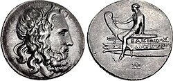 A tetradrachm minted during the reign of Antigonus III Doson (r. 229–221 BC), possibly at Amphipolis, bearing the portrait image of Poseidon on the obverse and on the reverse a scene depicting Apollo sitting on the prow of a ship