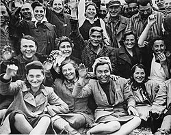 Female prisoners at Dachau wave to their liberators.