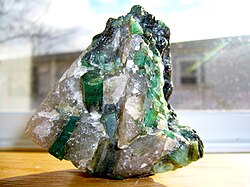 Brazilian emerald (grass-green variety of the mineral beryl) in a quartz-pegmatite matrix with typical hexagonal, prismatic crystals[12]