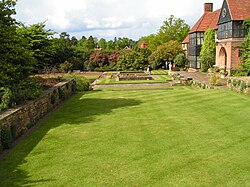 green lawn with trees to the left and a house on the right