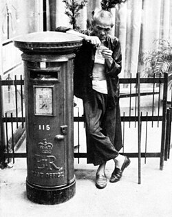 A man leaning on a Royal Mail post box in Hong Kong, 1962