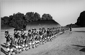 A line of several Indigenous men at a traditional ceremony