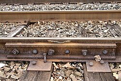 Mainline, six-bolt rail joint on a segment of 155 lb/yd (76.9 kg/m) rail. The alternating bolt head orientation prevents joint separation should a derailed wheel strike the bolts. The electrical bonding jumper connects the two rails to maintain continuity of the track circuit.