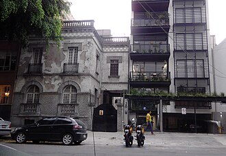 A building in Mexico City in need of repainting beside a modern loft tower