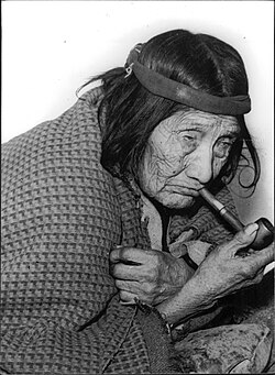 Elderly Tehuelche woman smoking a tobacco pipe