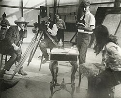 Left to right: Griffith, cameraman Billy Bitzer (behind Pathé camera), Dorothy Gish (watching from behind Bitzer), Karl Brown (keeping script) and Miriam Cooper (in profile) in a production still for Intolerance (1916)