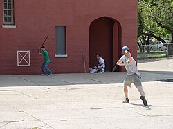 Stickball is a common street variant of baseball which often features impromptu adaptations. (Note the painted strike zone on the wall behind the batter.)
