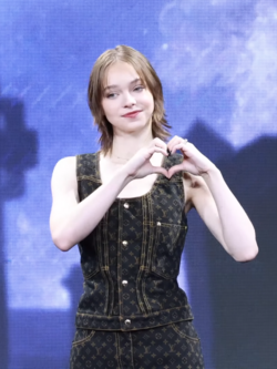 American actress Emma Myers making a heart sign at a Wednesday promotional event in 2025