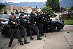 Police officers and U.S. Marshals deputies conducting an arrest in Salinas, California, carrying a variety of weaponry