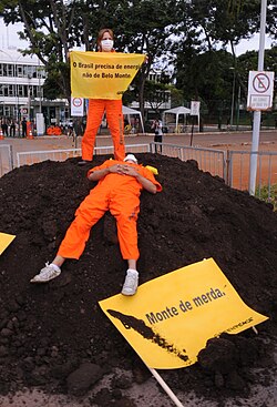 Protestors against the dam. The sign translates to "Beautiful pile of shit".