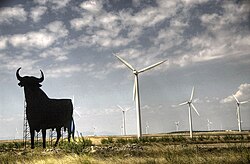 Wind turbines are typically installed in windy locations. In the image, wind power generators in Spain, near an Osborne bull.