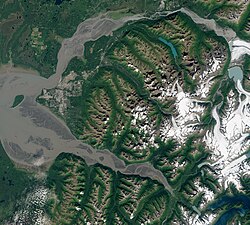 Satellite view taken August 2020. The Municipality encompasses the entire land mass between the Knik River and Knik Arm (top), and the Turnagain Arm (bottom), with the Mat-Su borough to the north, the Kenai Peninsula to the south, and Whittier just east of the mountains (lower right). The city proper lies on the coastal alluvial plain at the headwaters of Cook Inlet, between the two arms (left of center).