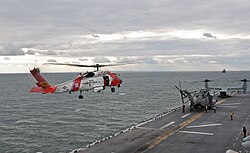A U.S. Coast Guard helicopter preparing to land on the flight deck of the amphibious assault ship USS Wasp