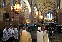 Lutheran priest and altar servers at Saint Mary's Church in Sigtuna, Sweden, standing in the narthex during recessional hymn at the end of Epiphany Day Mass