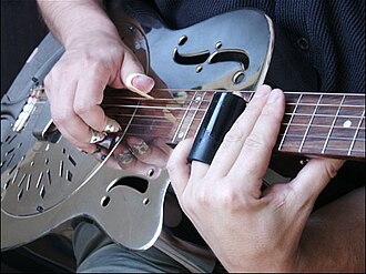 Example of a bottleneck slide, with fingerpicks and a resonator guitar made of metal