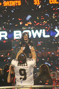 Drew Brees holding up his son after winning Super Bowl XLIV.