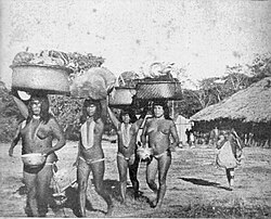 Four woman in traditional garments are seen carrying things