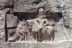 Rock-face relief at Naqsh-e Rustam of Iranian emperor Shapur I (on horseback) capturing Roman emperor Valerian (kneeing) and Philip the Arab (standing).