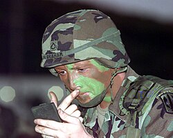 photo of a soldier applying camouflage face paint