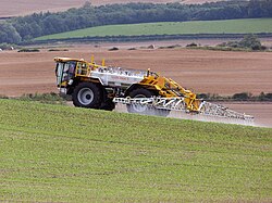 A self-propelled crop sprayer spraying pesticide on a field