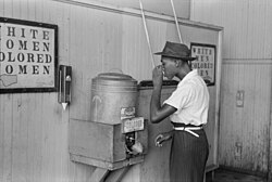 An African American drinks out of a segregated water cooler designated for "colored" patrons in 1939 at a streetcar terminal in Oklahoma City.