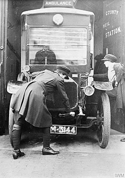 An ambulance driver using a crank to start the engine (1918)