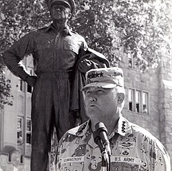 Schwarzkopf speaking at West Point in the shadow of the Douglas MacArthur statue