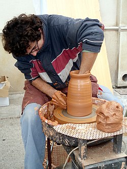 A ceramist moulding clay on a pottery wheel.