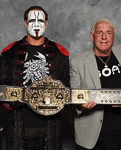 Sting and Ric Flair holding a replica of the Big Gold Belt, which represented six different championships
