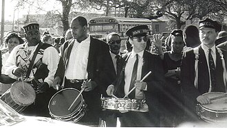 Drummers at the funeral of jazz musician Danny Barker in 1994. They include Louis Cottrell, (great-grandson of New Orleans' innovative drumming pioneer, Louis Cottrell, Sr. and grandson of New Orleans clarinetist Louis Cottrell, Jr.) of the Young Tuxedo Brass Band, far right; Louis "Bicycle Lewie" Lederman of the Down & Dirty Brass band, second from right.