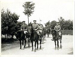 Field Marshal Sir John French with two ADCs, on horseback, Blendecques, France, 18 August 1915. In the background is his escort of troopers from the 4th Cavalry and the 15th Lancers. The Indian figure just behind the main group is Sirdar Bahadur Khwaja Mahomed.