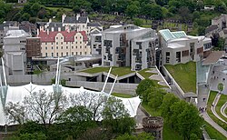 An aerial view of the Scottish Parliament Building complex. The red tiles of Queensberry House are visible between the MSP Office block at the back of the complex and the Tower and Canongate Buildings at the front which house the debating chamber and committee rooms.