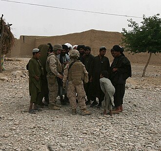 A platoon commander of the 1st Marine Logistics Group, with the battalion interpreter, gather intelligence from local Afghans during a combat logistics patrol to the area, May 9, 2010.