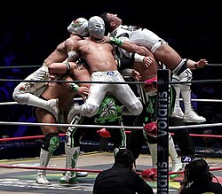 The Mexican wrestlers Gran Guerrero, Último Guerrero, and Euforia performing a triple team move on their opponents