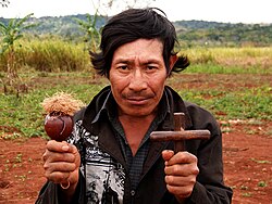 Guarani medicine man holding cross and maraca