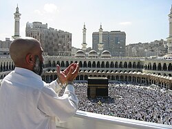 Supplicating pilgrim at Al-Masjid Al-Ḥarām (The Sacred Mosque) in Mecca. The Kaaba (the holiest site of Islam) is the cubic building in front of the pilgrim.