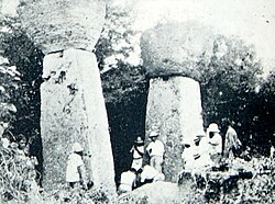 Ruins of Guma Taga on Tinian. The pillars/columns are called latte (pronounced læ'di) stones, a common architectural element of prehistoric structures in the Mariana Islands, upon which elevated buildings were built. Earthquakes had toppled the other latte at this site by the time this photo was taken; an earthquake in 1902 toppled the one seen on the left, and today only the one on the right remains standing.