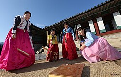 Koreans wearing hanbok and playing yut during the Korean New Year.