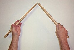 A pair of drumsticks held in traditional grip.